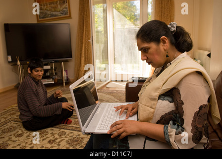 Mother who cares for her 24 year old daughter with Cerebral palsy taking time out to work on her laptop Stock Photo
