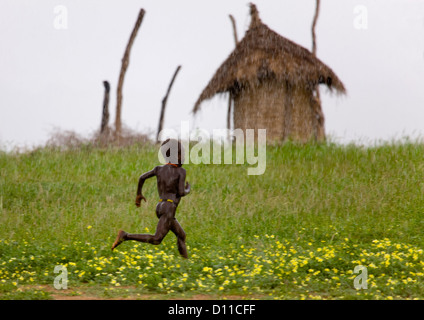 Kid From Karo Tribe Running Under The Rain, Korcho Village, Omo Valley, Ethiopia Stock Photo