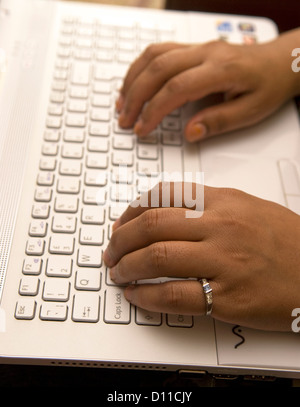 Mother who cares for her 24 year old daughter with Cerebral palsy taking time out to work on her laptop Stock Photo