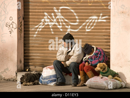 Homeless couple - man and woman  with dogs sitting beside a shop doorway in Santiago, Chile South America Stock Photo