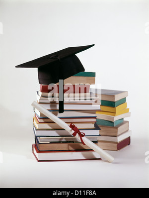 1970s GRADUATION STILL LIFE OF DIPLOMA AND MORTARBOARD ON TOP OF PILE STACK OF BOOKS Stock Photo