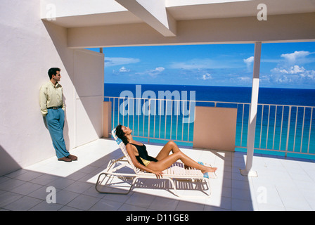 MAN AND WOMAN ON SUNNY DECK BALCONY OVERLOOKING THE OCEAN Stock Photo