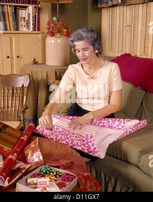 1960s MIDDLE AGED WOMAN WRAPPING GIFT CHRISTMAS WRAPPING PAPER GIFT WRAP PRESENT Stock Photo