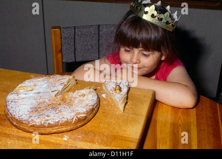 Girl with La Galette des Rois (French King Cake) with Feve and Crown usually shared on the Epiphany to celebrate the arrival of the Three Wise men in Stock Photo