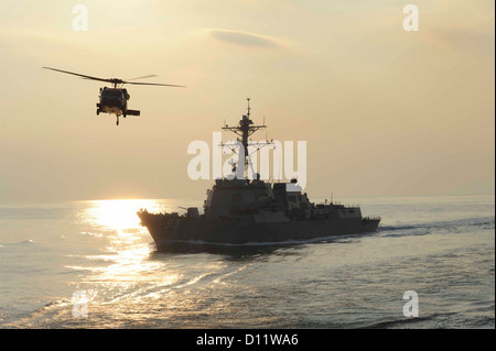 An MH-60S Knighthawk from the Eightballers of Helicopter Sea Combat Squadron (HSC) 8 assigned to the Military Sealift Command fast combat support ship USNS Bridge (T-AOE 10) flies by the Arleigh Burke-class guided-missile destroyer USS Farragut (DDG 99) d Stock Photo