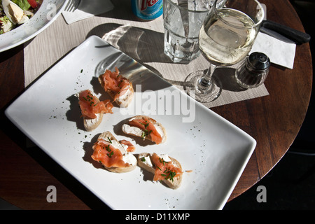 plate of delicious bruschetta topped with smoked salmon cream cheese & herbs graces outdoor table of cafe in Roma District Stock Photo