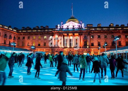 Ice skaters at rink at Somerset House at night The Strand London England UK