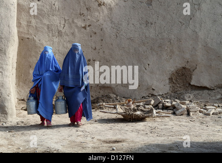 Afghan women wearing traditional full body covering called Burqa carry milk pails from a USAID milk processing October 22, 2012 in Jebul Saraj, Afghanistan Stock Photo