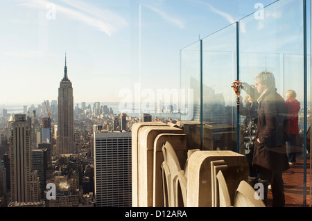 tourists standing on 'top of the rock' looking south at the Empire State Building