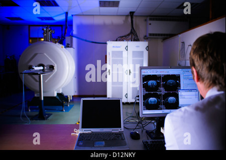 Scientist or technician assesses the computer image on screen monitor from a small bore Magnetic Resonance Imaging (MRI) scanner Stock Photo