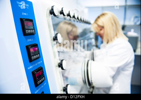 female scientist working at temperature controlled incubator in science lab Stock Photo
