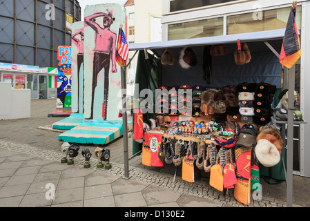 Stall selling DDR army and war memorabilia as souvenirs near sections of the original wall on Friedrichstrasse, Berlin, Germany Stock Photo