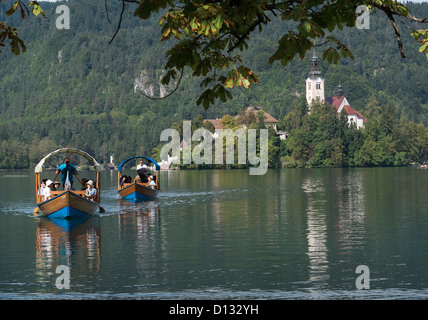 The traditional way to reach the lake's island is by a pletna boat. Two parties return to the lake shore on a pletna. Stock Photo