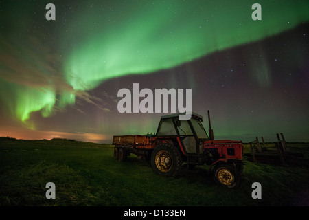 Aurora Borealis Northern Lights in the night sky over a field with a disused red truck. Stock Photo