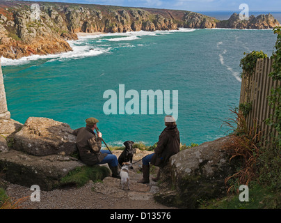 Porthcurno Bay and Logan Rock, Cornwall. Walkers pause to rest and admire the view. Stock Photo