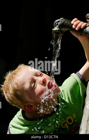A young boy drinking from a water fountain Stock Photo