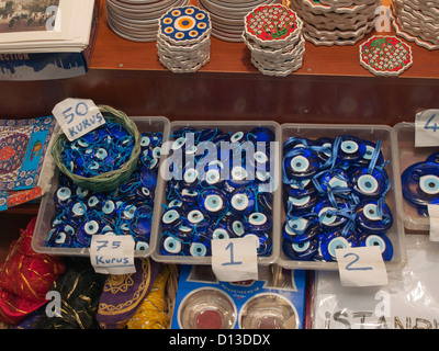 blue glass pendants protecting against the evil eye sold with other souvenirs in a market in Istanbul Turkey Stock Photo