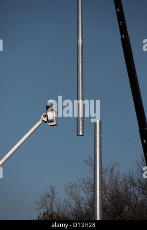 A worker is lifted in a crane to install and secure the lighting for ...
