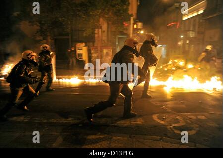 Athens, Greece. 6th December 2012. Policemen walk along a burning street during clashes between police and rioters in the evening on the fourth anniversary of the death of Alexandros Grigoropoulos in Athens Greece on 06.12.2012. Alexandros Grigoropoulos was killed on 06.12.2008 at the age of 15 years by a bullet from a police weapon. Stock Photo