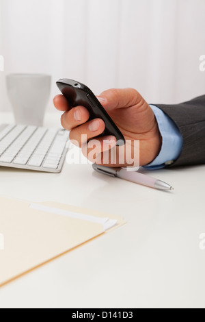 USA, Illinois, Metamora, Man texting on his mobile in office Stock Photo