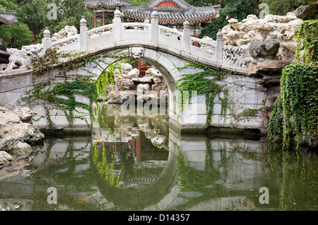 Arch bridge with reflection in Chinese garden. Stock Photo