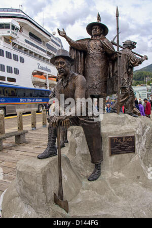 July 6, 2012 - Ketchikan Gateway Borough, Alaska, US - A life-size bronze sculpture â€œThe Rockâ€, designed to honor 7 Ketchikan Alaskan pioneers stands at Berth 3 of the cruise ship docks and is one of the areas most recognizable landmarks. The Holland America Lines cruise ship â€œZaandamâ€ is visible in background. The principle artists were David Rubin, Terry Pyles and Judy Rubin and the figures represent Chief Johnson, The Logger, The Fisher, The Miner, The Aviator, A Native Elder Woman, and an Elegant Lady. (Credit Image: © Arnold Drapkin/ZUMAPRESS.com) Stock Photo