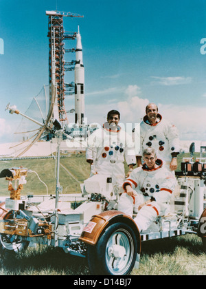 Apollo 17 crew photographed with a Lunar Roving vehicle and Saturn V rocket. They are Eugene A Cernan (seated), commander, Ronald E. Evans (standing on right), command module pilot, and Harrison H. Schmitt, (standing on left) lunar module pilot. The crew spent 12.5 days in space, including three days on the lunar surface and is the last time man set foot on the moon. Stock Photo