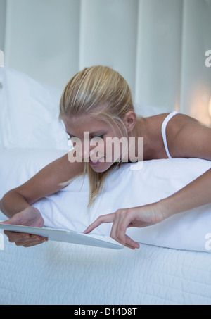Woman using tablet computer on bed Stock Photo