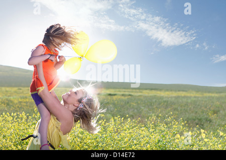 Sisters playing in field of flowers Stock Photo