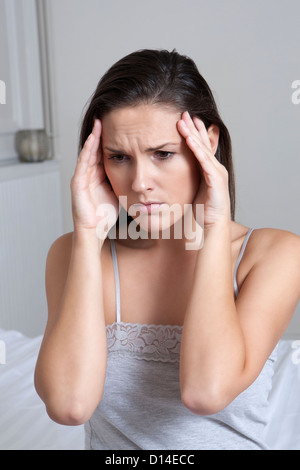 Woman rubbing temples in bed Stock Photo - Alamy