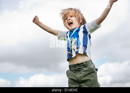 Boy with medals cheering outdoors Stock Photo