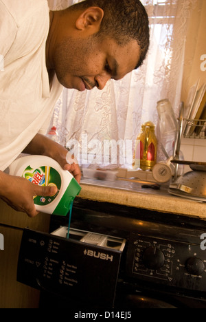 Husband who cares for his disabled wife at home putting the washing on, London, UK. Model Released image. Stock Photo