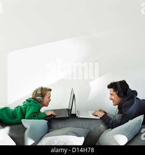 Father and son using laptops on sofa Stock Photo