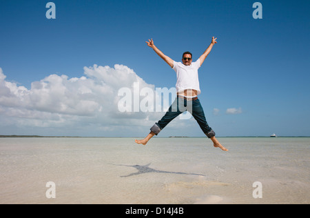 Man jumping in water on tropical beach Stock Photo