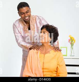 A lovely mature Indian woman enjoying a shoulder massage from her son at home Stock Photo