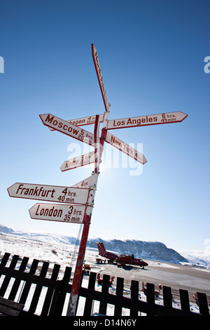 Post with road signs by wooden fence Stock Photo