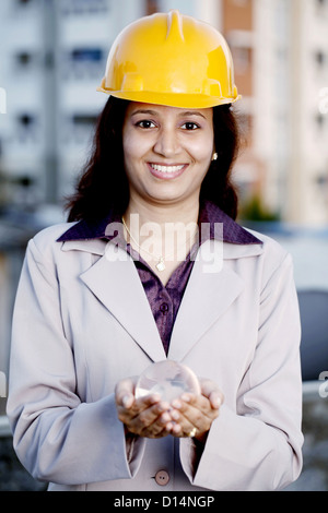 Indian female construction engineer holding a glass globe on her hands Stock Photo