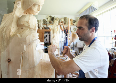 Sculptor chiseling figure from wood Stock Photo