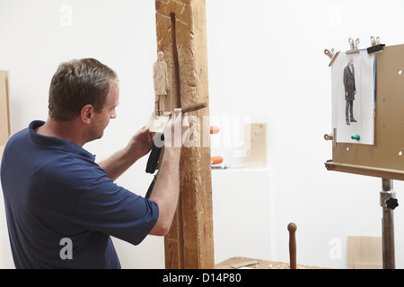 Worker chiseling figure from wood Stock Photo