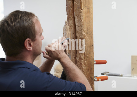 Worker chiseling figure from wood Stock Photo