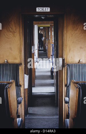 looking down walkway of the interior of an old steam train carriage