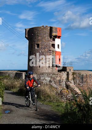 Woman cyclist at Archirondel Tower, le Havre de Fer, Jersey east coast, Channel islands, UK Stock Photo