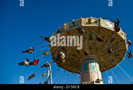 Fairground swing carousel thrill ride spinning fast against clear blue sky Stock Photo