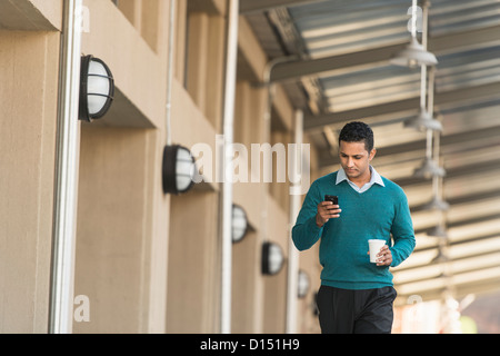 USA, New Jersey, Jersey City, Man walking outside building and text messaging Stock Photo