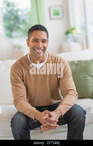 USA, New Jersey, Jersey City, Portrait of smiling man sitting on sofa Stock Photo