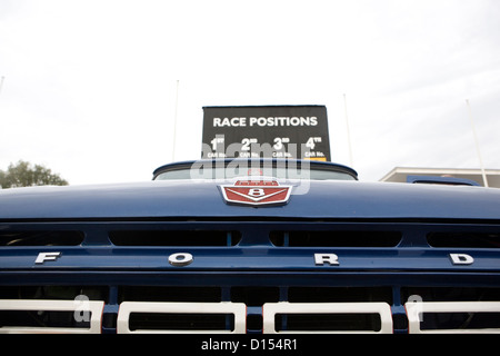 A Ford badge and grill on the front of a classic blue pickup truck. Stock Photo