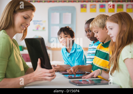 USA, New Jersey, Jersey City, School children (8-9) with female teacher working with computers Stock Photo