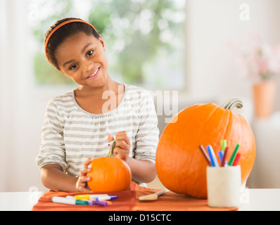 USA, New Jersey, Jersey City, Portrait of smiling girl (6-7) making Jack-o-lantern Stock Photo
