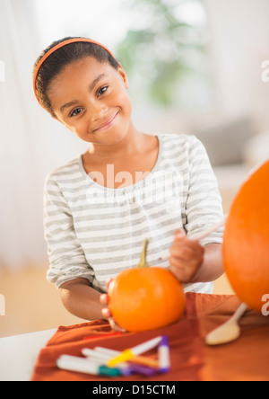 USA, New Jersey, Jersey City, Portrait of smiling girl (6-7) making Jack-o-lantern Stock Photo