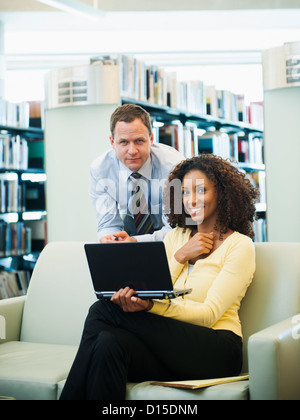 USA, Utah, Salt Lake City, Man and woman using laptop in library Stock Photo